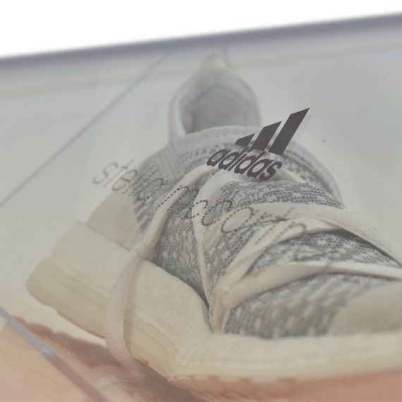 side view of Adidas white trainer in clear Perspex box