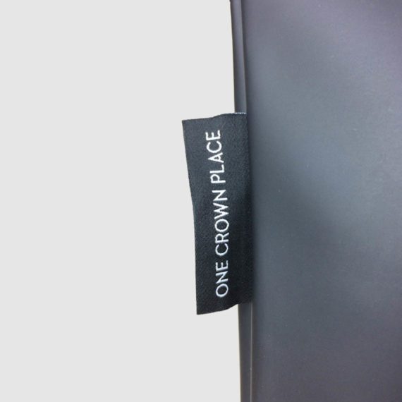 black woven label with white text logo ONE CROWN PLACE